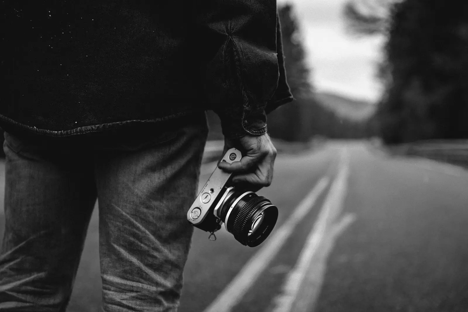 Fotograaf met camera in de hand op een lege weg