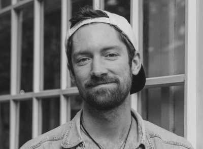 Zwart-wit portret van een lachende man met pet